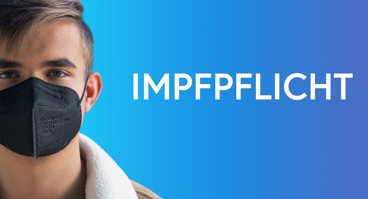Schriftzug Impfpflicht, Mann mit Schutzmaske
