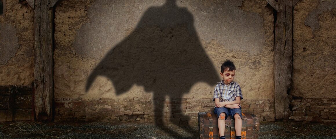 Junge vor Mauer mit Schatten von Batman