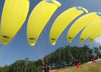 Gruppen von Gleitschirmfliegern mit gelben Schirmen