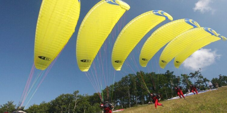 Gruppen von Gleitschirmfliegern mit gelben Schirmen