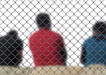 Flüchtlinge hinter einem Zaun