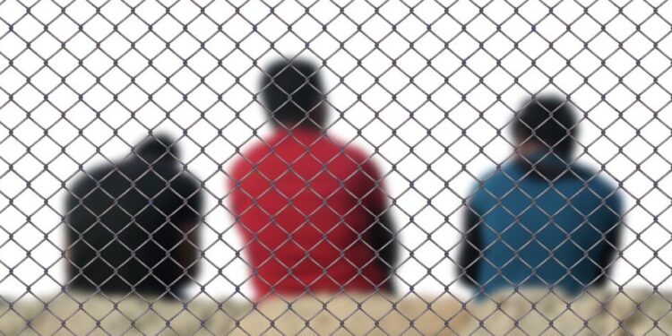 Flüchtlinge hinter einem Zaun