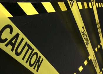 Gelbes Absperrband mit der Aufschrift "Caution" vor schwarzem Hintergrund