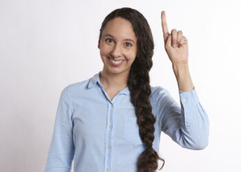 Frau hebt Finger, Symbolbild für "Idee"