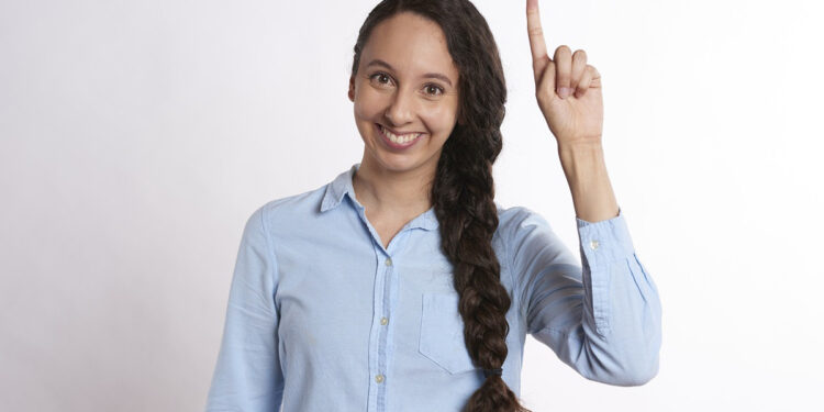 Frau hebt Finger, Symbolbild für "Idee"