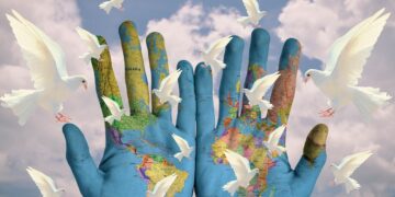 Hände mit aufgemalter Weltkarte und weißen Tauben, Symbolbild für Ökologie, Frieden, Nachhaltigkeit
