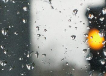 Gelbe Ampel hinter Scheibe mit Regentropfen