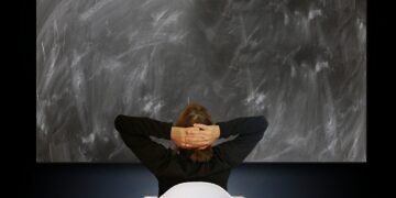 Rückenansicht einer Person vor leerer Schultafel