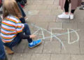 Bodenbild_ Kind streicht AfD-Schriftzug mit Kreide durch