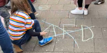 Bodenbild_ Kind streicht AfD-Schriftzug mit Kreide durch