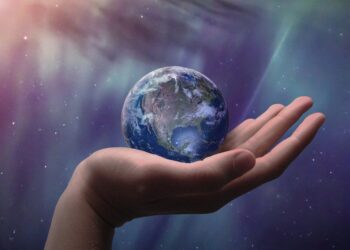 Kleiner Globus in einer Hand vor dem Hintergrund des Weltalls