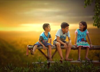 Drei Kinder auf einer Bank im Sonnenuntergang reden miteinander