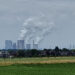 Braunkohlenkraftwerk hinter grüner Wiese und Dorf