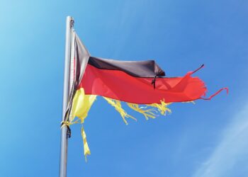 Zerrissene Deutschland-Fahne flattert im Wind an einem Fahnenmast