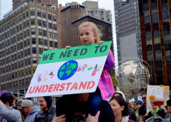 Kind mit Schild "We need to understand" auf einer Demonstration