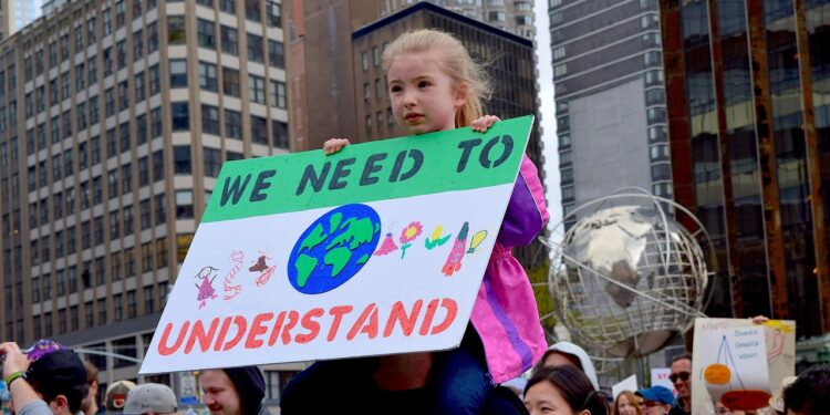 Kind mit Schild "We need to understand" auf einer Demonstration