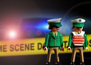 3 Polizisten (Playmobil) vor gelben Absperrband mit Aufschrift "Crime Scene"