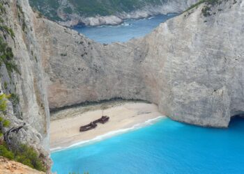 Schiffswrack auf einem Sandstrand in einer von hohen Felsen umgebender Bucht