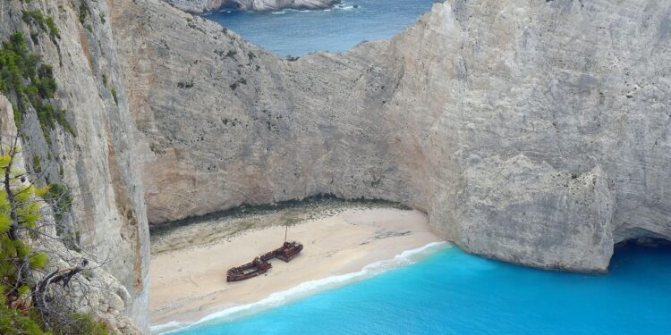 Schiffswrack auf einem Sandstrand in einer von hohen Felsen umgebender Bucht