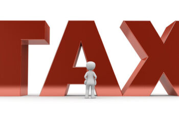 Vor einem riesigen Schriftzug in 3D "TAX" steht eine kleine weiße Figur