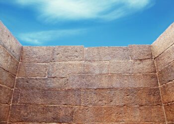 Hohe Mauer mit einem Stück Himmel über der MAuerkrone.