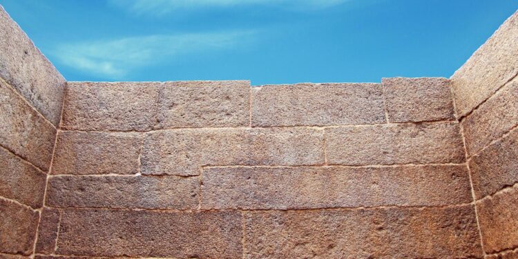 Hohe Mauer mit einem Stück Himmel über der MAuerkrone.