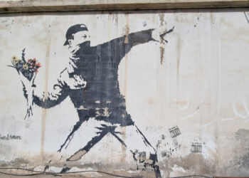 Vermummter Aufständischer wirft Blumenstrauss. Benksy-Graffiti in Bethlehem