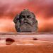 Büste bzw. Kopf von Karl Marx in dystopischer Landschaft mit rotem Himmel im Hintergrund