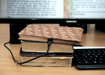 alte Bücher vorneinem Computerbildschirm und mit einem Netzkabel verbunden