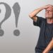 Mann schlägt sich Hand auf die Stirn, daneben stehen ein großes Ausrufezeichen und ein Fragezeichen, Symbolbild für Fehler oder Zweifel