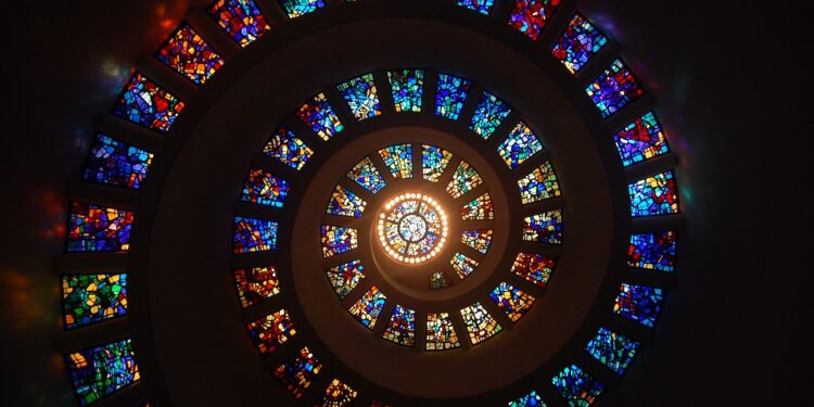 Kreisförmiges Fenster, umrandet von spiralförmigen weiteren bunten Fenstern, alle im Stil von Kirchenfenstern