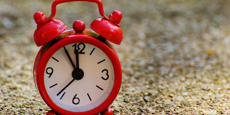 Ein roter Wecker, der 5 vor 12 anzeigt.
