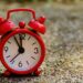 Ein roter Wecker, der 5 vor 12 anzeigt.