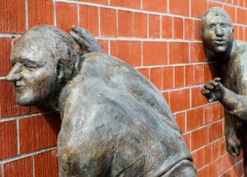 Skulptur. zwei alte horchen an einer roten Ziegelwand