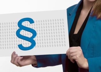 Frau im Anzug hält eine Präsentationstafel mit einem großen Paragraphen-Zeichen auf vielen kleinen Paragraphen-Zeichen