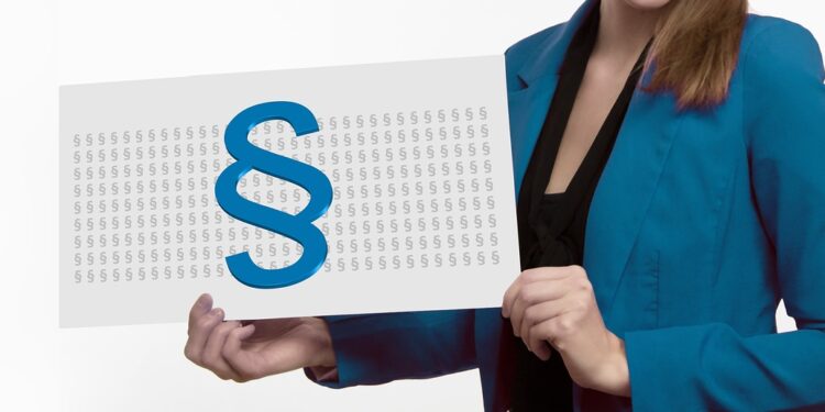 Frau im Anzug hält eine Präsentationstafel mit einem großen Paragraphen-Zeichen auf vielen kleinen Paragraphen-Zeichen