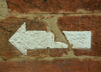 Weißer Abbiegepfeil nach links auf roter Ziegelsteinmauer