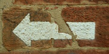 Weißer Abbiegepfeil nach links auf roter Ziegelsteinmauer