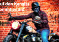 Rocker auf Harley Davidson vor Mauer mit der Aufschrift "Auf den Kanzler kommt es an!"