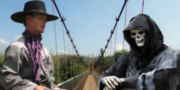 Ein Coboy und ein Sensenmann verhandeln auf einer Brücke