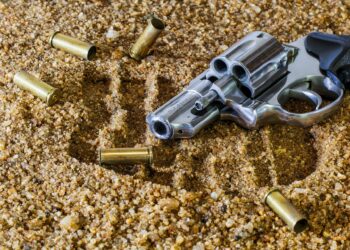 Revolver mit Patronenhülsen im Sand