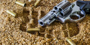 Revolver mit Patronenhülsen im Sand