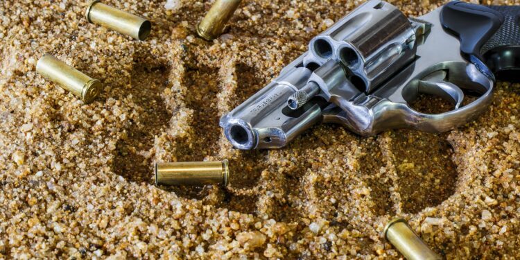 Revolver mit Patronenhülsen im Sand