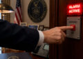 Hand, offensichtlich in einem Büro der US-administration drückt einen Alarm-Knopf. AI generiert mit ChatGPT