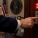 Hand, offensichtlich in einem Büro der US-administration drückt einen Alarm-Knopf. AI generiert mit ChatGPT