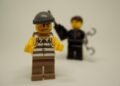 Dieb, im Hintergrund wartet ein Polizist mit Handschellen