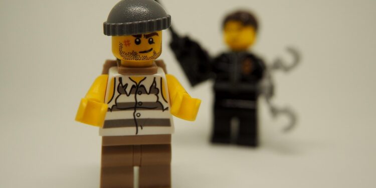 Dieb, im Hintergrund wartet ein Polizist mit Handschellen