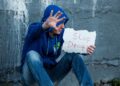 Symbolbild: Süchtiger Mann hebt abwehrend die Hand und hält in der anderen Hand ein Bild "Stop Drugs"