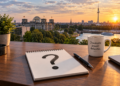 Skyline von Berlin, davor ein Schreibtisch mit einem Schreibblock, auf dem ein großes Fragezeichen steht. KI generiert mit ChatGPT.