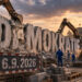 Schriftzug "DEMOKRATIE" vor dem Deutschen Bundestag im Hintergrund wird von Baggern abgerissen. Männer in blauen Arbeitsanzuügen beaufichtigen die Arbeit. An der Abrißstelle hängt ein Schild 6.9.2026, KI generiert mit ChatGPT